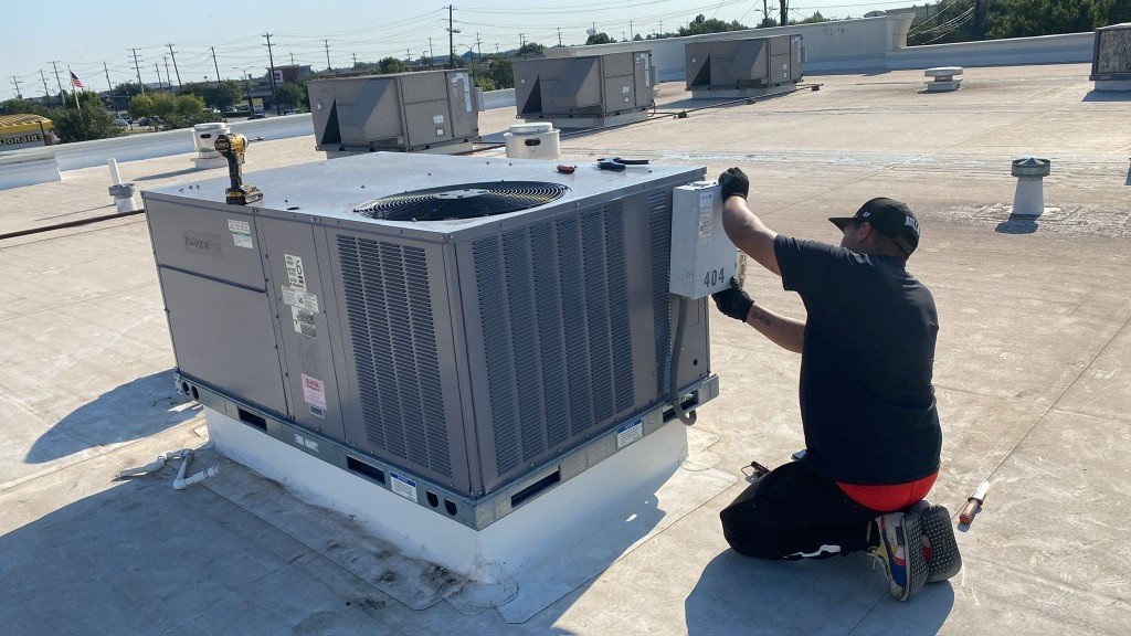 Technician repairing a commercial rooftop HVAC packaged unit